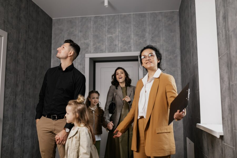 A woman in a mustard-colored suit showing potential buyers a home.